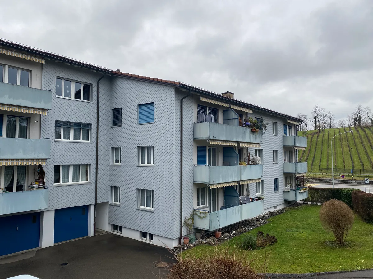 Zwei Mehrfamilienhäuser, die zusammengebaut, aber versetzt sind. Sie sind etwas in die Jahre gekommen.